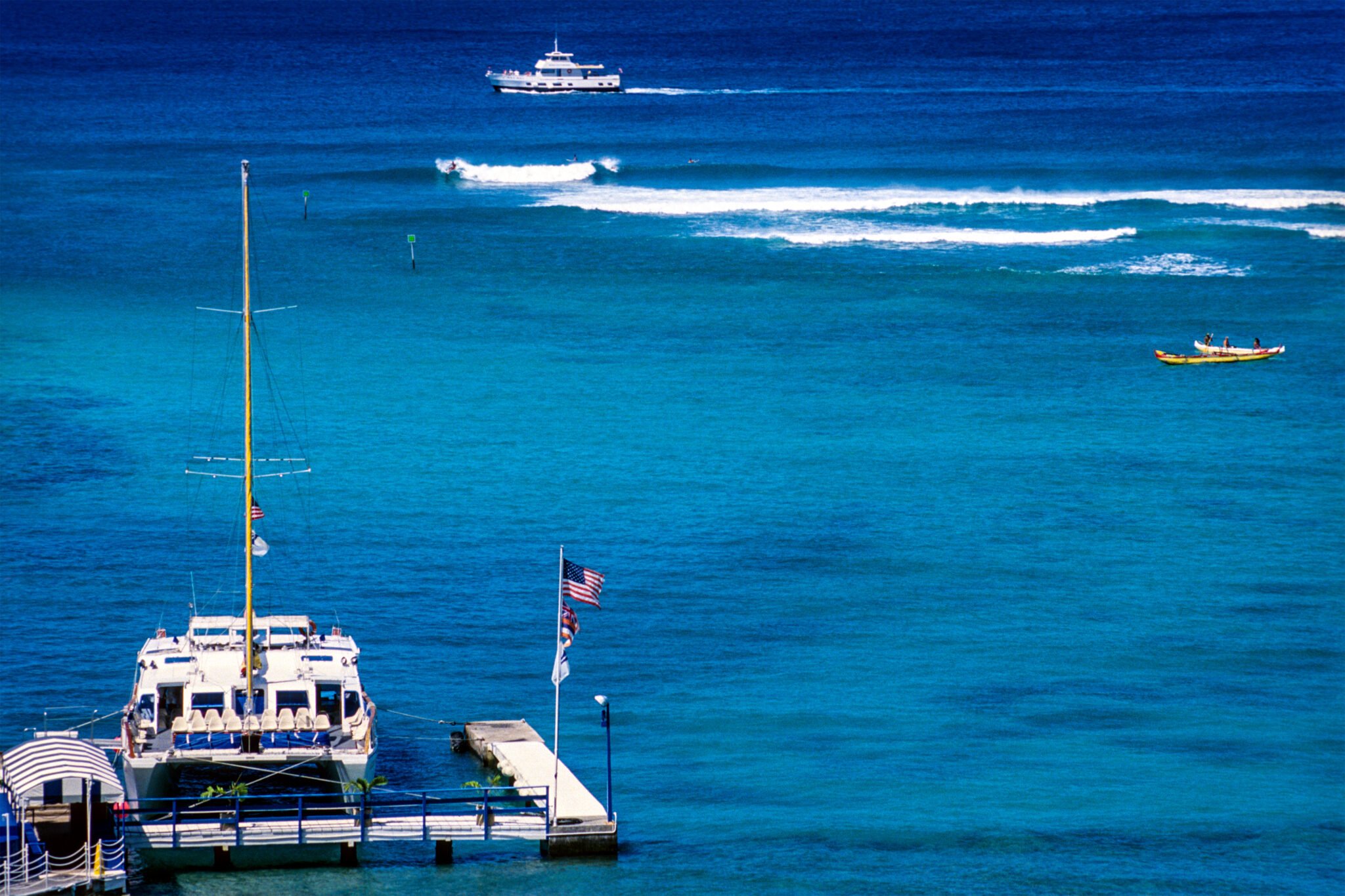 USA, Honolulu, Hawaii, Oahu, Waikiki, boat dock and surfing waves. Honolulu Fishing Charters.